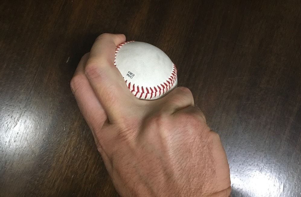 hand with a baseball demonstrating a sinker grip